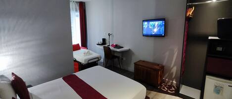 Una habitación de hotel con una cama, un escritorio, un televisor y un refrigerador.