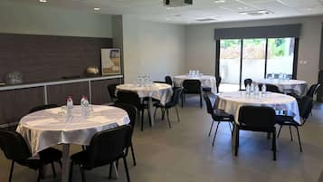 Conference room with round tables, black chairs, and projector for presentations.