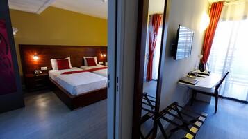 A hotel room with a wooden bed, bedside lamps, a desk with a chair, and a TV on the wall.