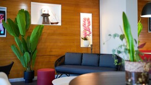 A modern interior with a wooden wall, a blue sofa, and potted plants. - Tulip Inn Sainte Clotilde La Reunion (Saint-Denis)