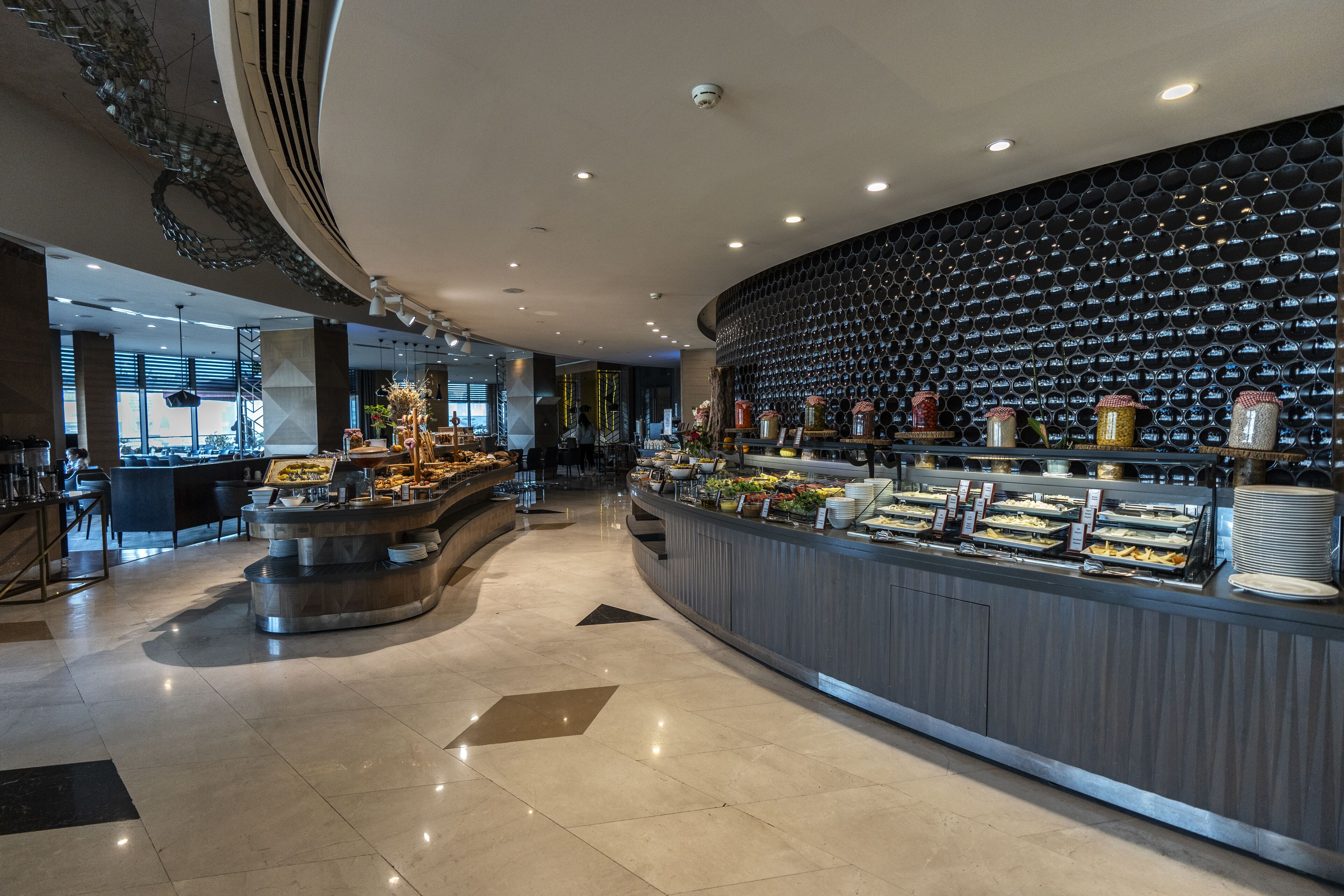 A modern buffet area with a variety of food options, a seating area, and a decorative ceiling.