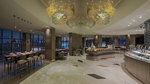 A modern hotel lobby with a central island bar, seating areas, and large windows offering city views. - Hilton Istanbul Kozyatagi (Istanbul)