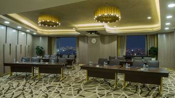 A conference room with two large tables, chairs, a clock, and a city view.