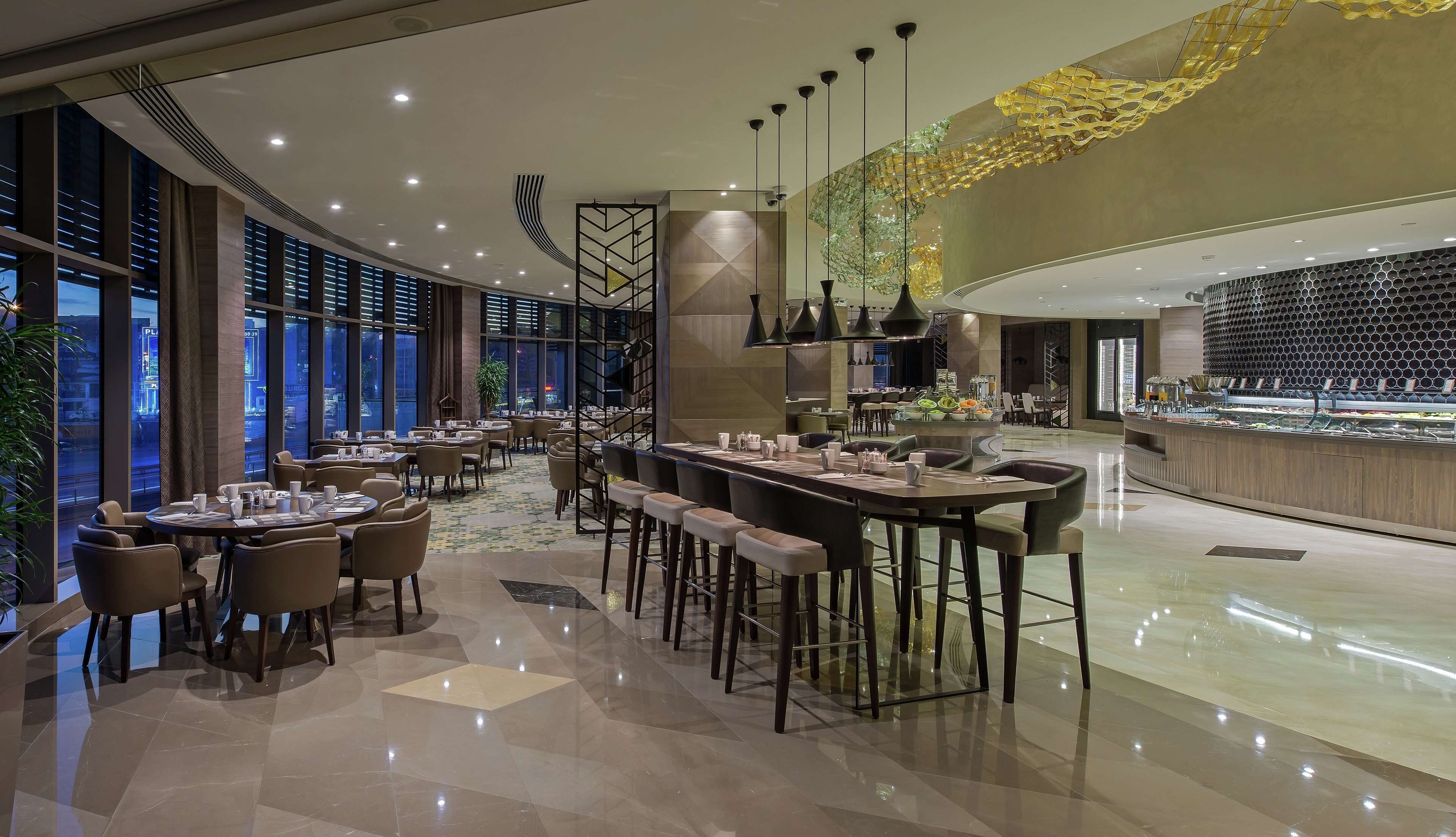 A modern restaurant with a variety of seating options, including round tables and bar stools.
