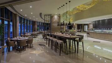 A modern restaurant with a variety of seating options, including round tables and bar stools.