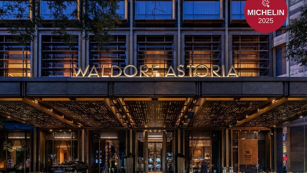 Exterior del hotel Waldorf Astoria con señalización iluminada y una fachada moderna.