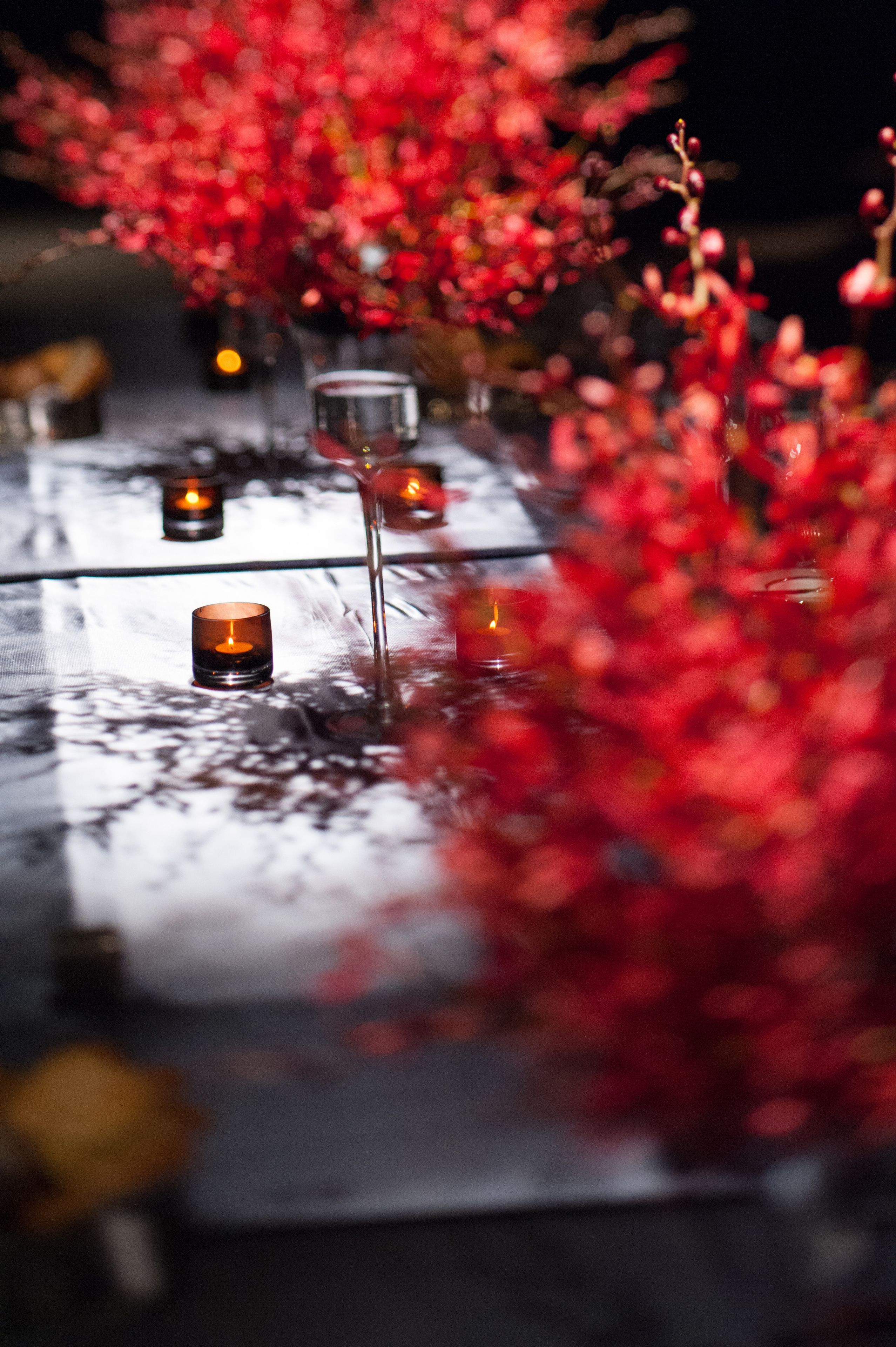 Una mesa con velas y flores rojas, creando un ambiente cálido.