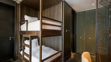 A bunk bed with a wooden frame and white bedding, a dark wooden door, and a patterned wall.