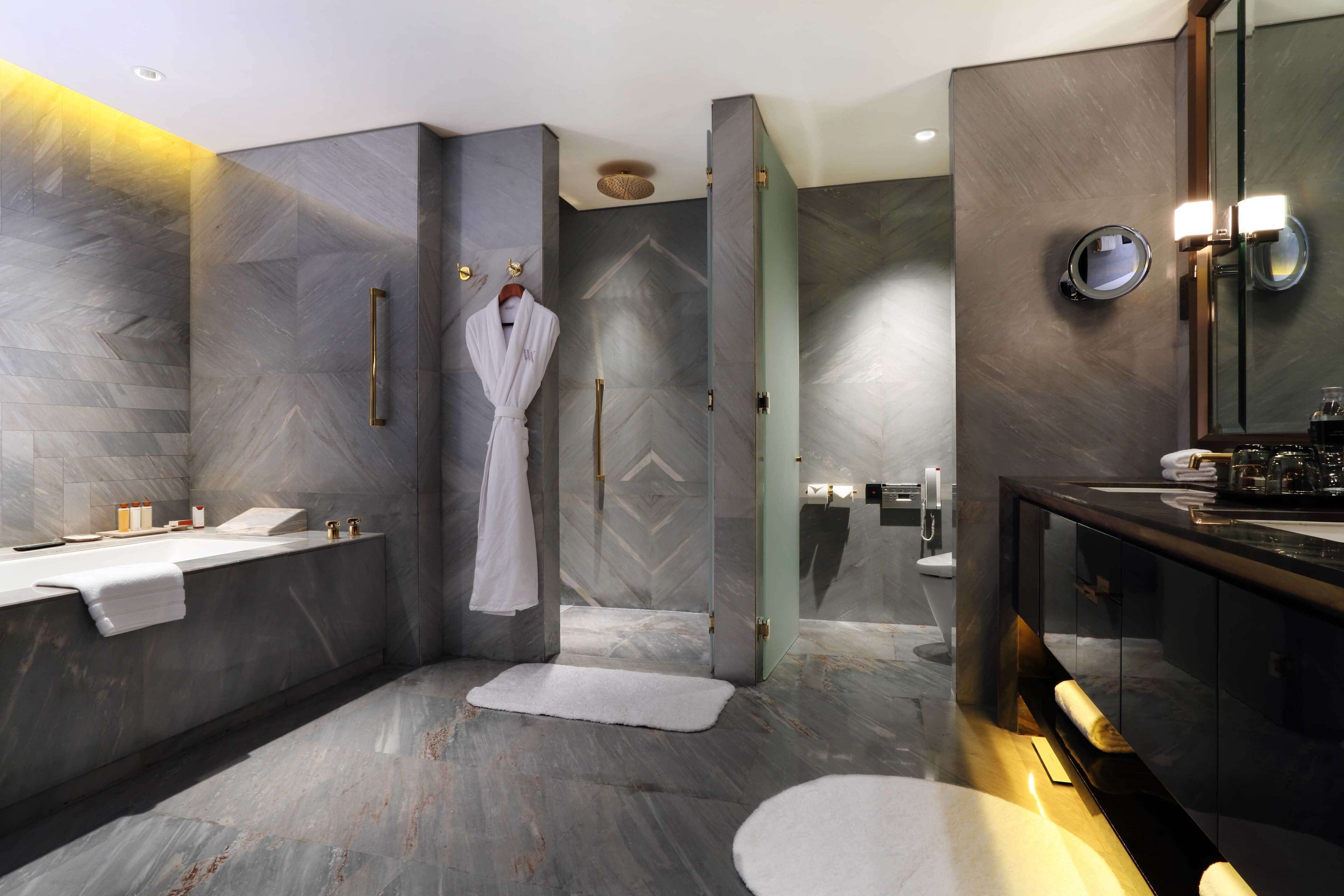 Un baño moderno con un espejo grande, una bañera, una ducha y un tocador con lavamanos.