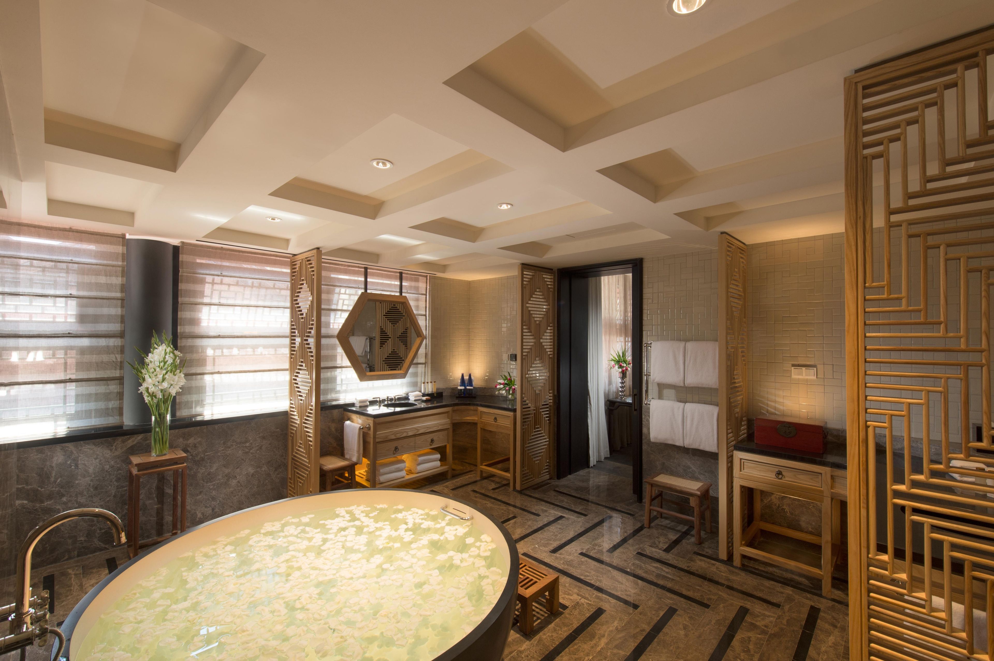A modern bathroom with a large bathtub, wooden decor, and a view of the city.