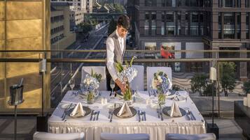 Mesa dispuesta para una cena formal, con vistas a la ciudad, incluyendo edificios modernos y un puente.