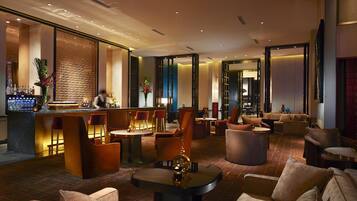 A modern hotel lobby with a bar, seating areas, and a reception desk.