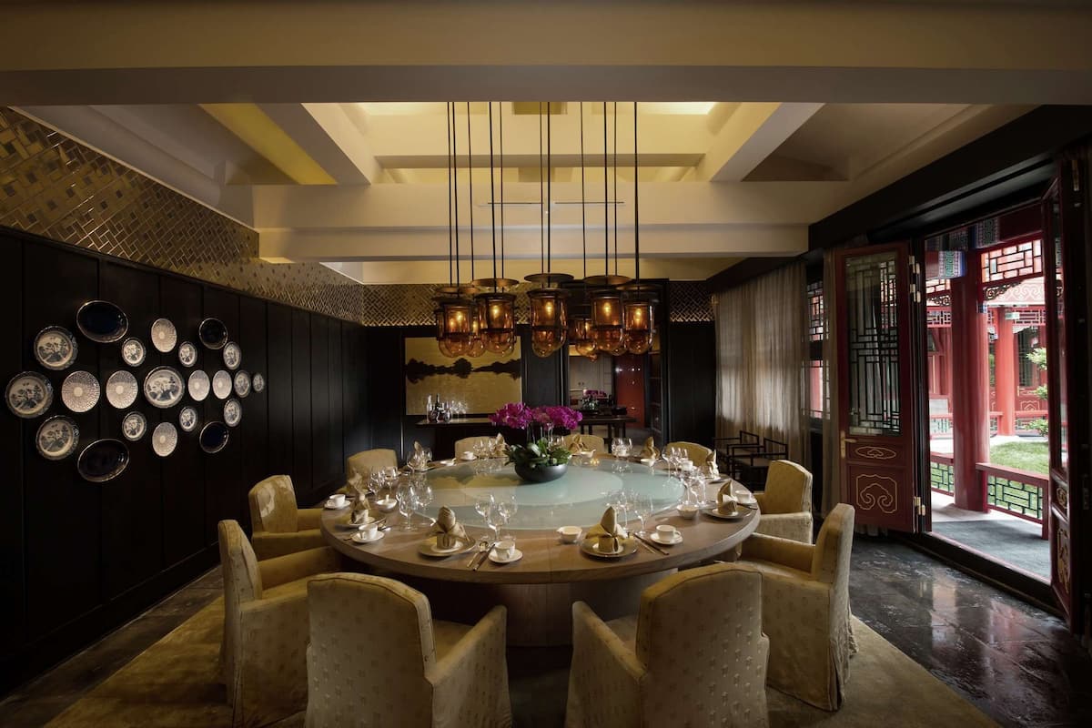 A dining area with a round table set for a meal, surrounded by chairs.