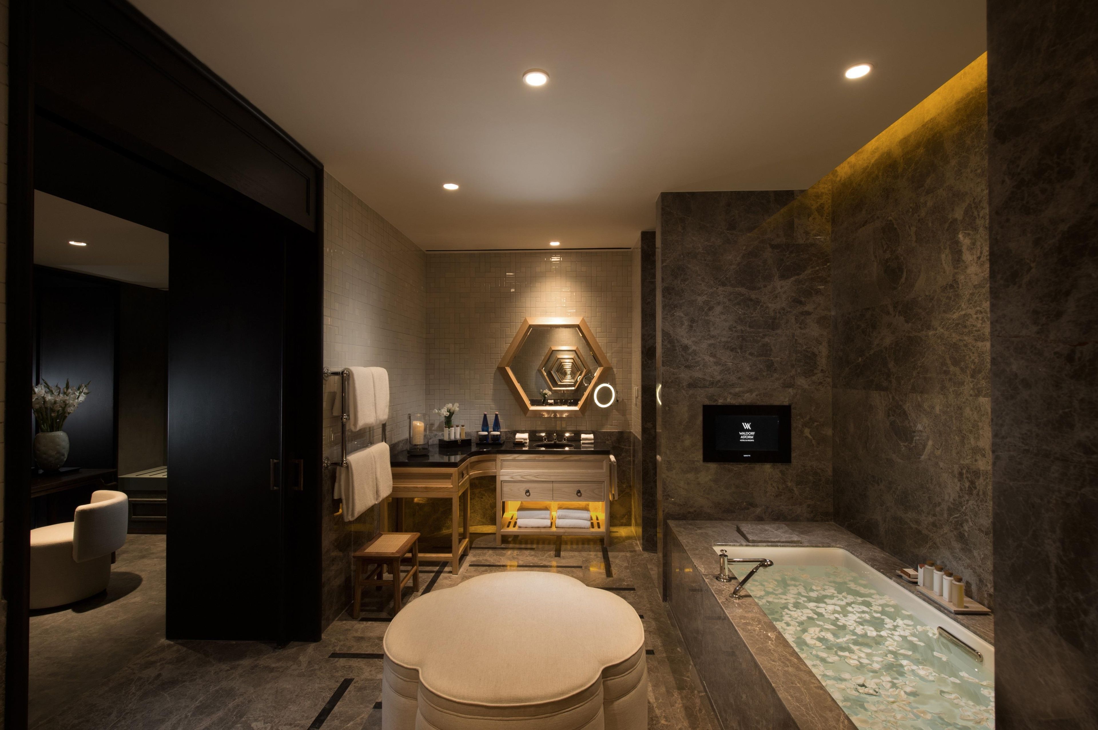 Un baño moderno con una bañera, un tocador con espejo y una zona de estar.