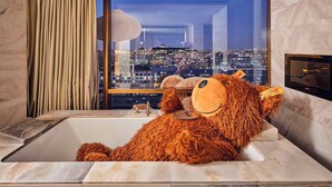 Un peluche en una bañera con vista a la ciudad.