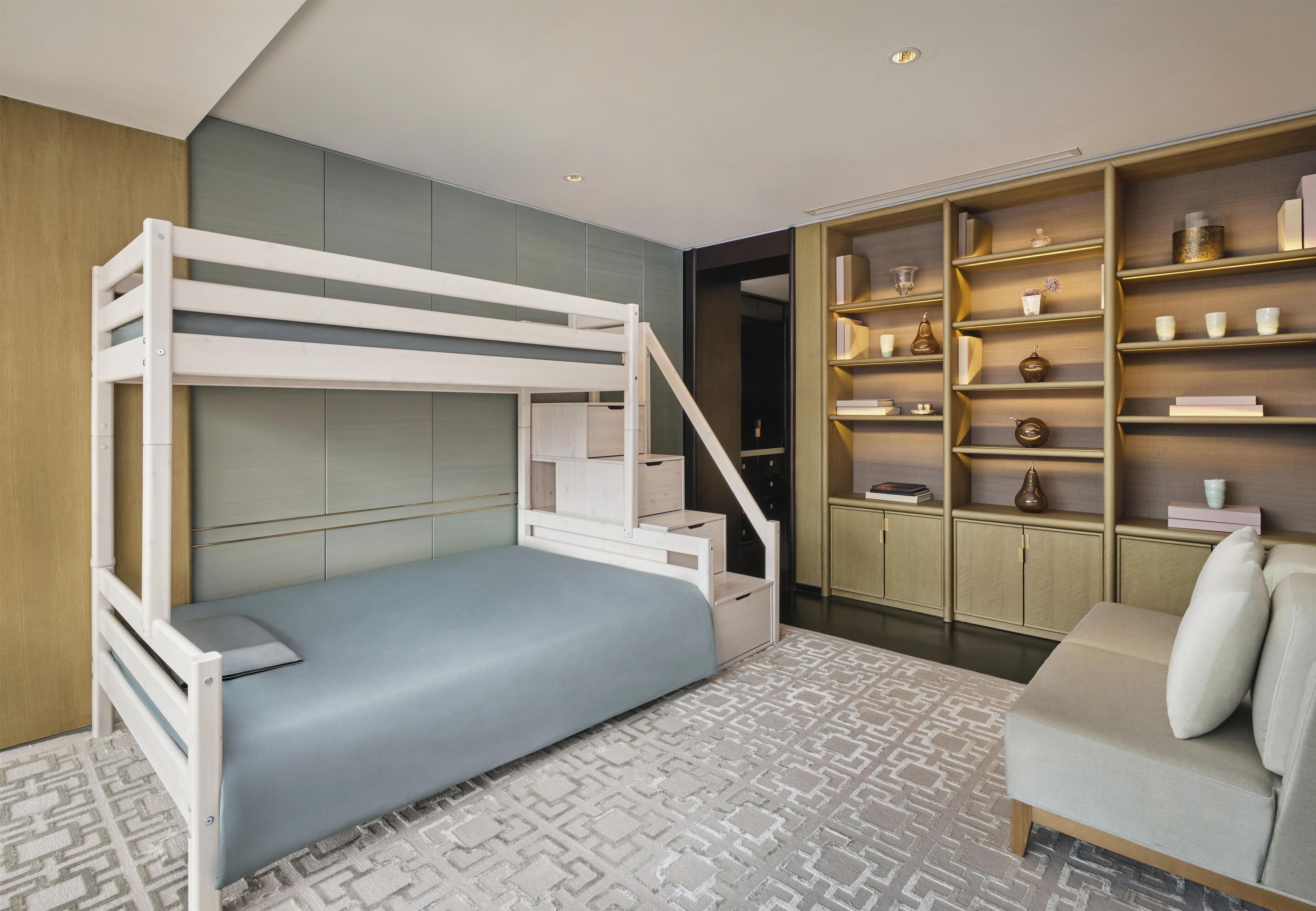 A bunk bed with a desk and shelving unit in a modern room with patterned carpet.