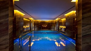 Una piscina interior moderna con paredes de mármol e iluminación.