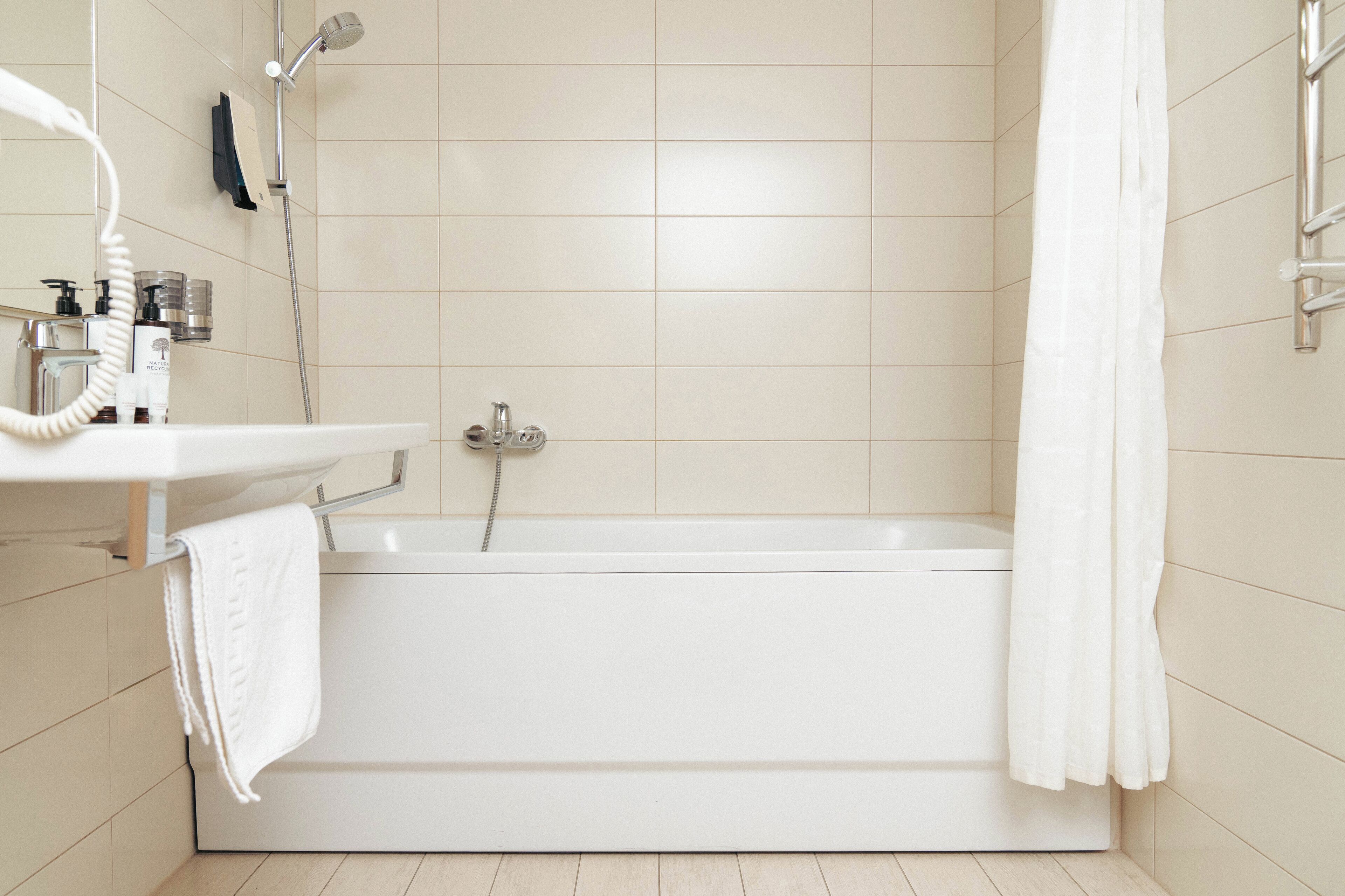 A modern bathroom with a bathtub, a sink with a mirror, and a showerhead.