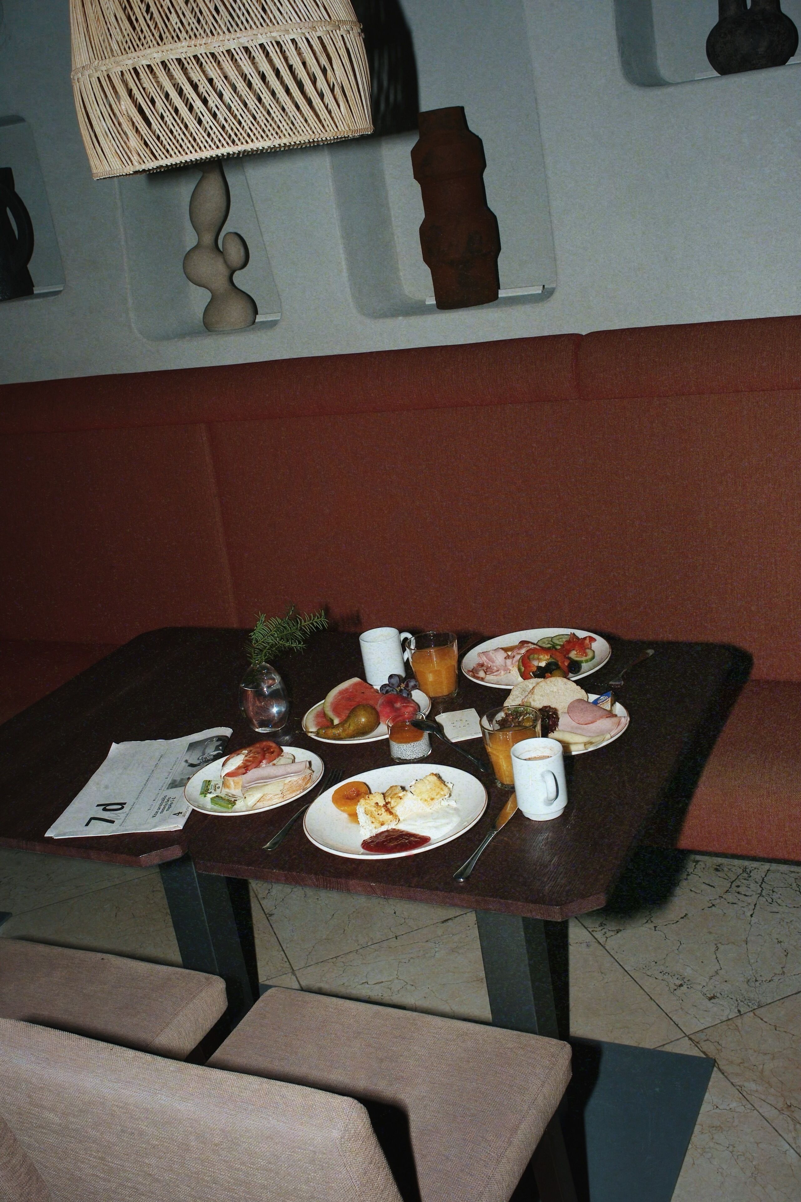 A dining table with plates of food, a vase with a plant, and a lamp.