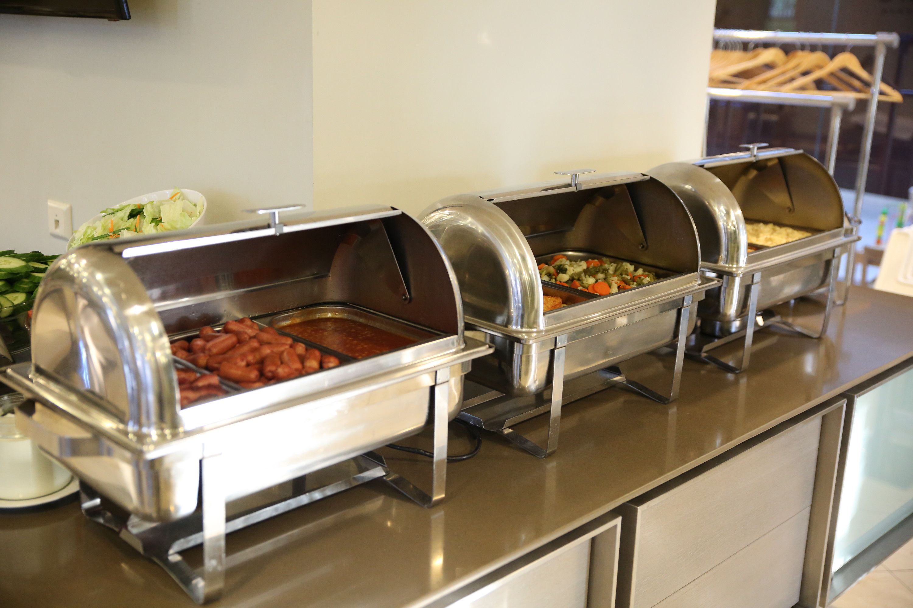Una barra de buffet con diferentes alimentos en estaciones de servicio cubiertas.