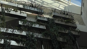 Um edifício moderno com teto de vidro e várias varandas com plantas.