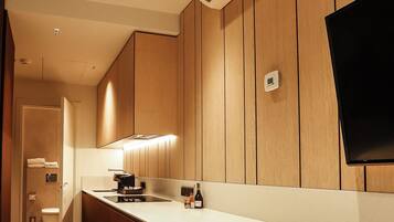 A modern kitchen with wooden paneling, a built-in air conditioner, a flat-screen TV, and a white countertop.