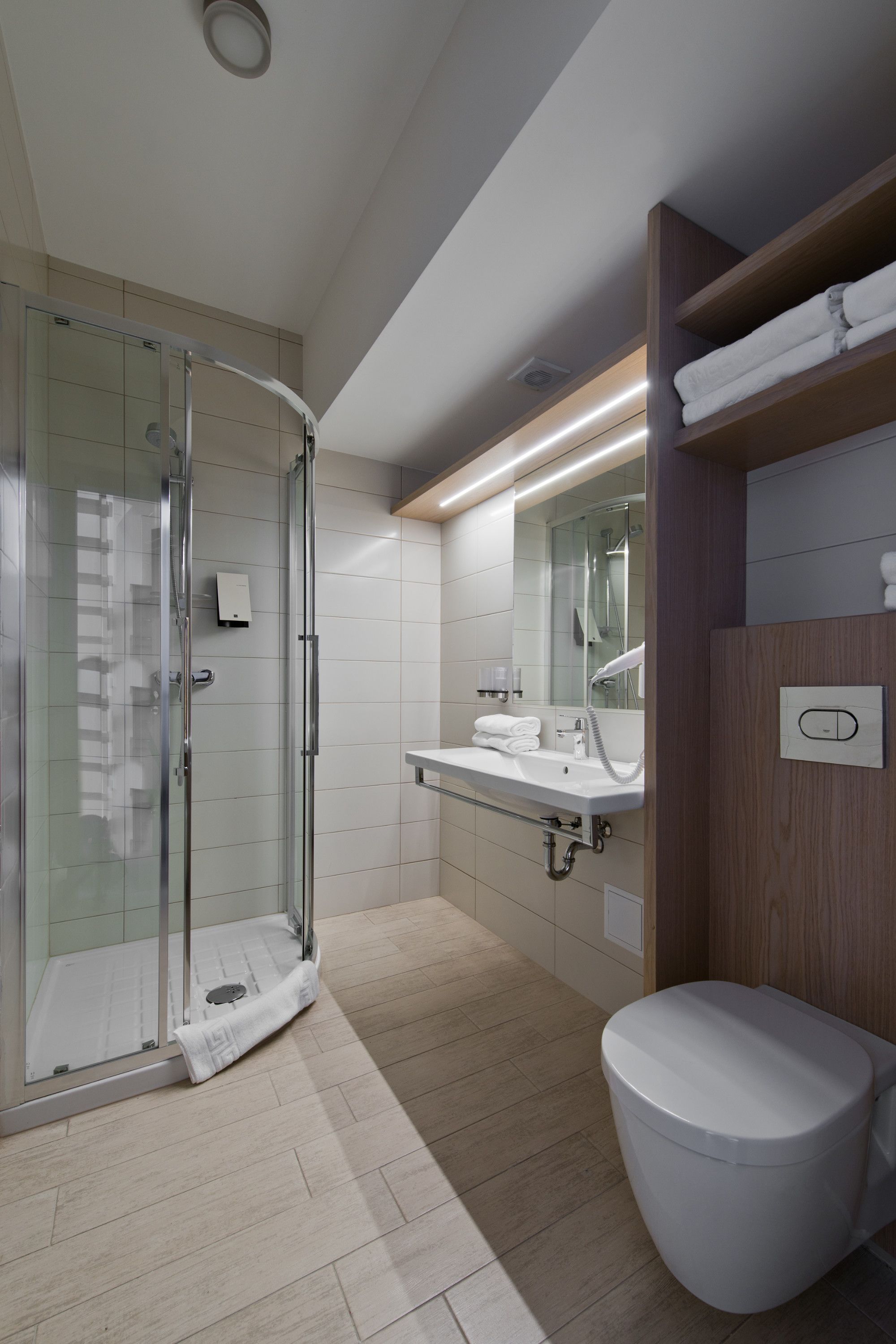 Un baño moderno con cabina de ducha de vidrio, un lavabo blanco y un inodoro.
