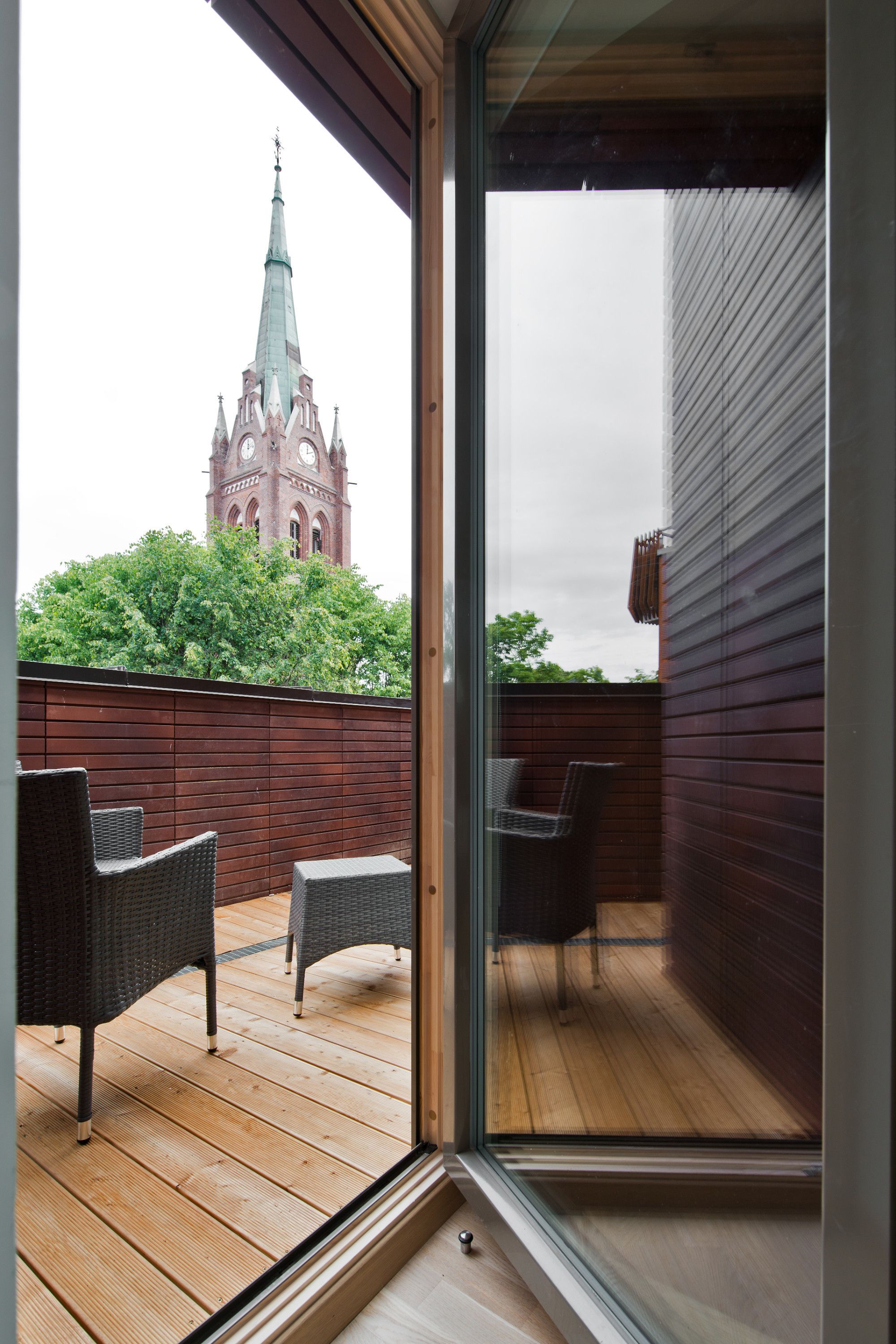 A balcony with wicker chairs and a view of a historic tower.
