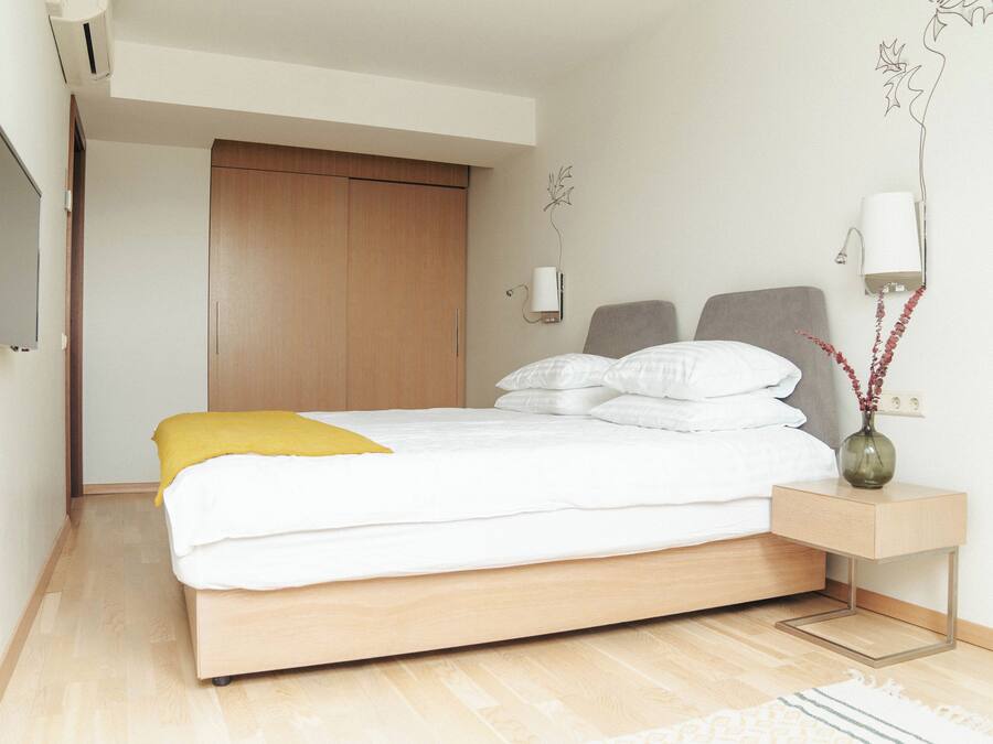 A modern bedroom with a bed, bedside table, and a wall-mounted lamp.