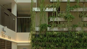 Uma área de estar moderna com sofás, cadeiras, um jardim vertical e entrada por porta de vidro.