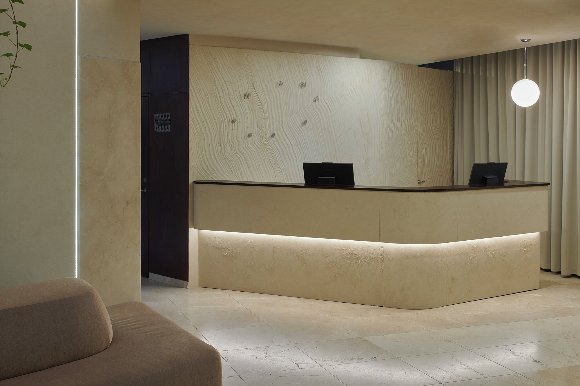 Uma mesa de recepção com painel de madeira, uma porta escura e um ponto de luz.