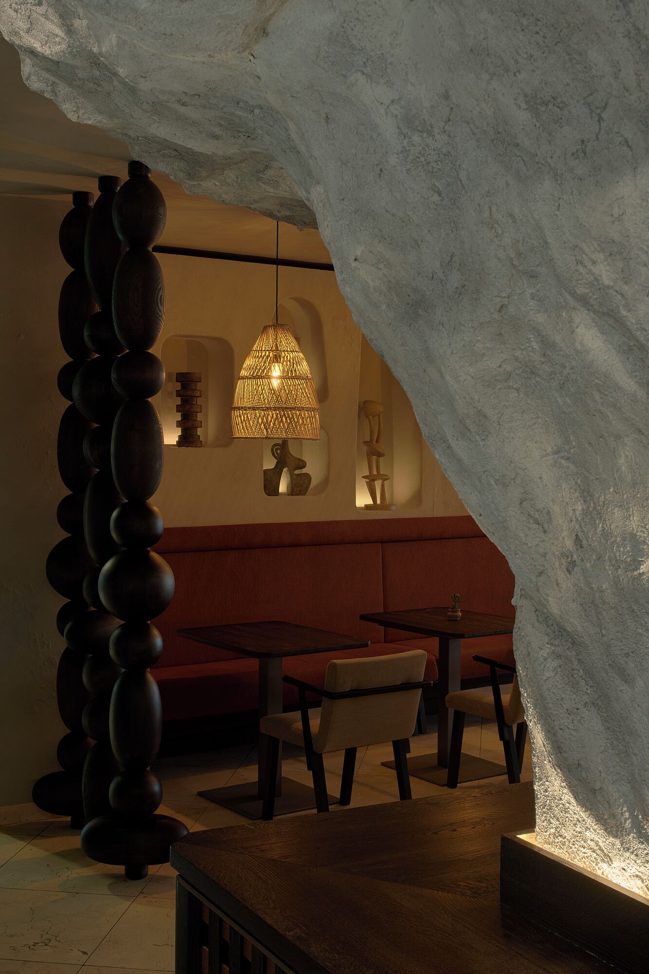 Un interior con pared de piedra, una lámpara colgante, una escultura de madera y una zona de estar.