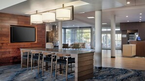 A modern bar area with a wooden bar counter, bar stools, and pendant lighting.