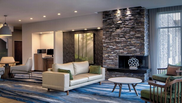 A modern living room with a stone fireplace, a sofa, a coffee table, and a TV.