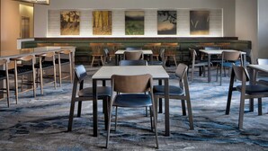 A modern dining area with booths and tables, a patterned carpet, and abstract wall art.