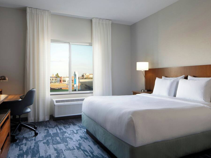 Une chambre d’hôtel avec un grand lit, un bureau, une chaise et une fenêtre avec des rideaux.