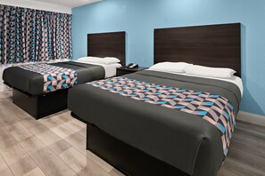 A hotel room with two beds, dark wooden headboards, and a patterned bedspread.