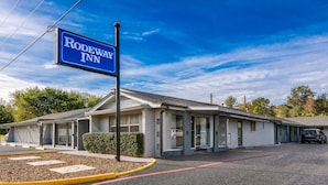 A motel with a sign reading "Rodeway Inn" in front of a building with multiple rooms and a parking area.