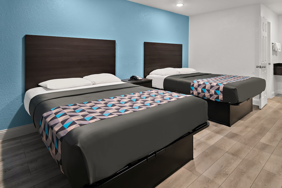 A hotel room with two beds, a nightstand, and a bathroom.