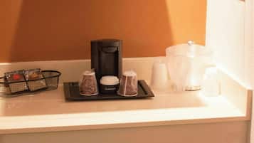 A kitchenette with a microwave on a glass shelf, a coffee maker, a mini-fridge, and various condiments.