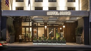 L’extérieur de l’hôtel Hugo se distingue par sa façade moderne, ses grandes fenêtres et son entrée accueillante.
