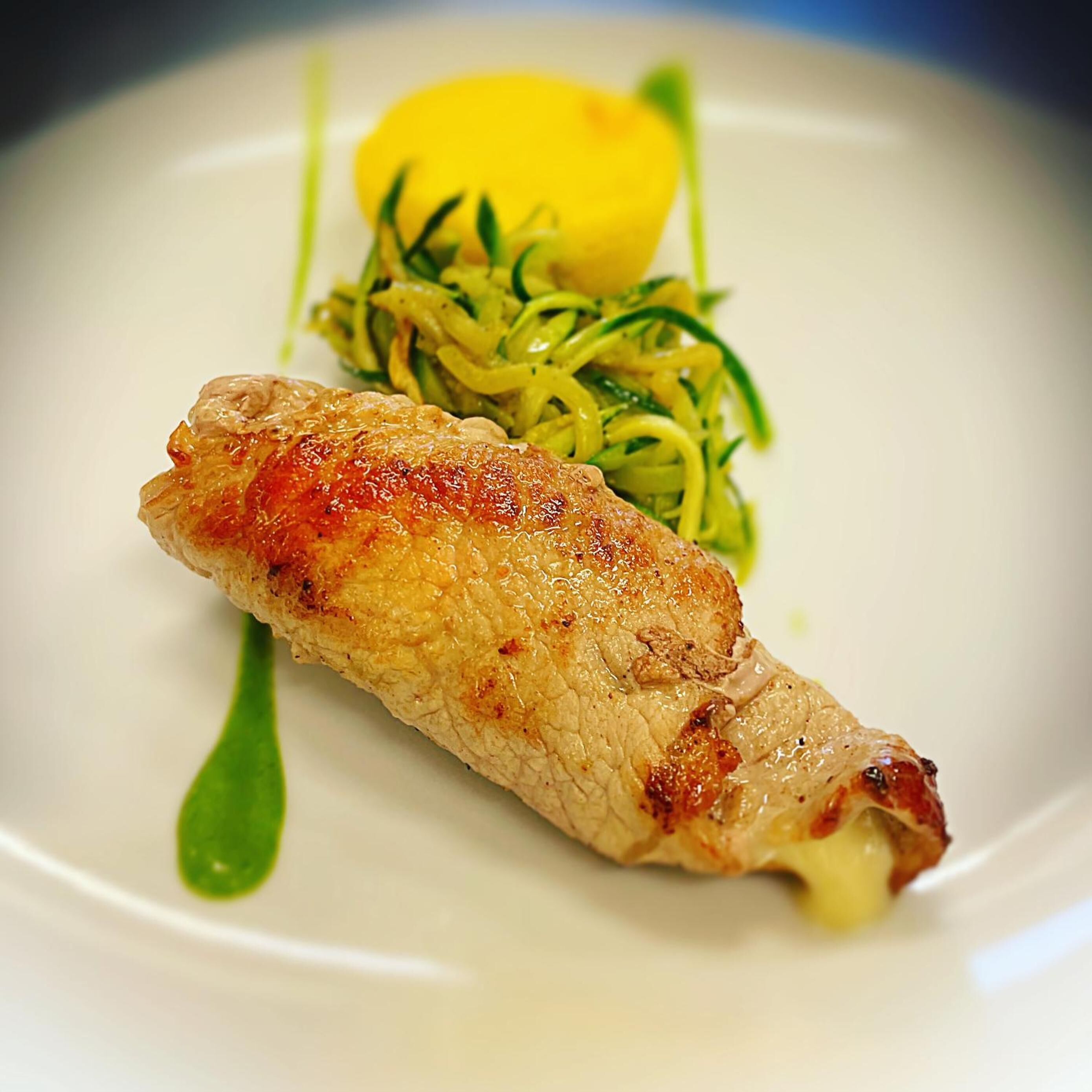 Un plato con un trozo de carne a la parrilla, un limón y una guarnición de verdura verde.