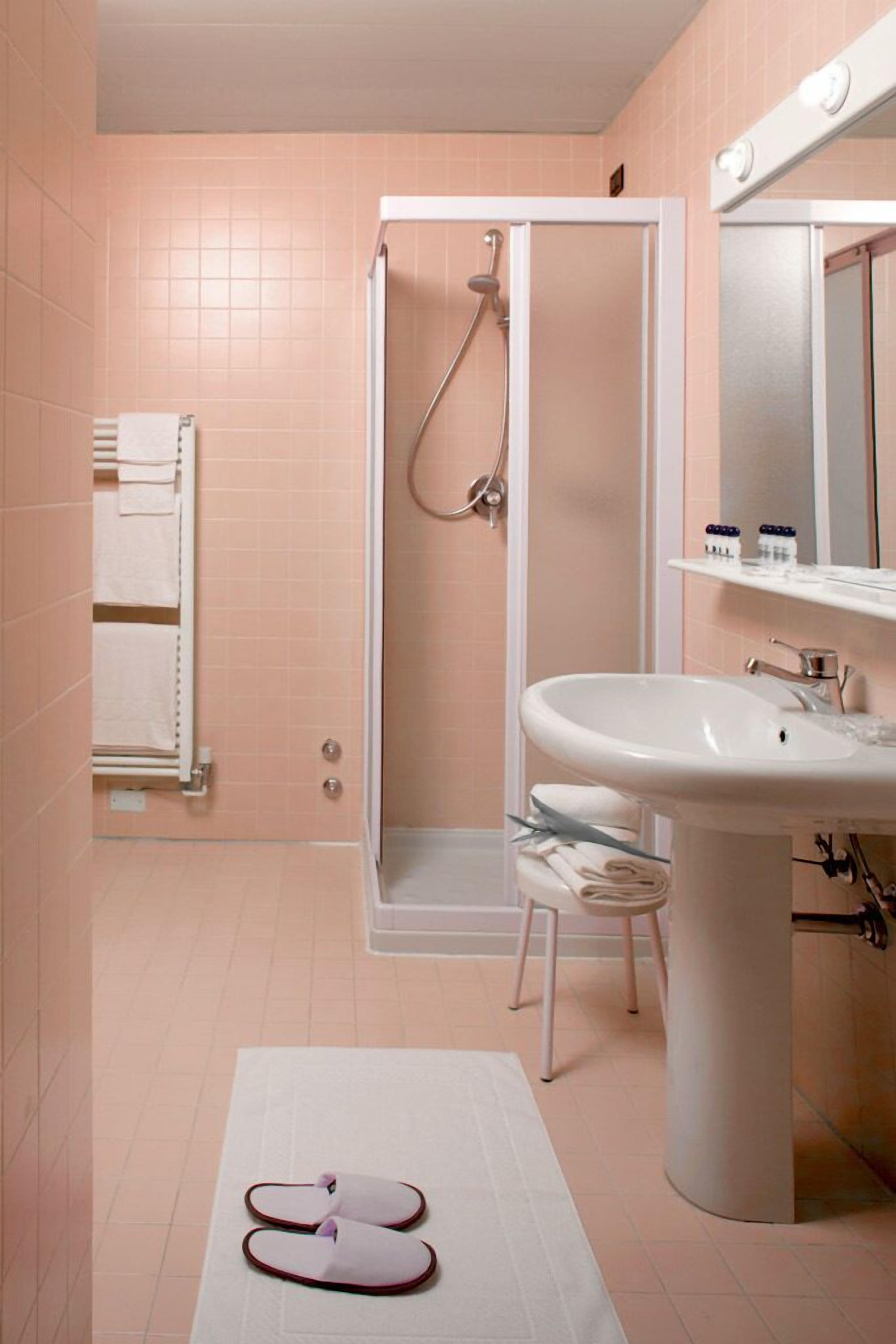 A bathroom with a shower, sink, and towel rack.