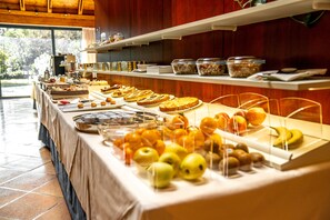 A buffet table with various food items and fruits.