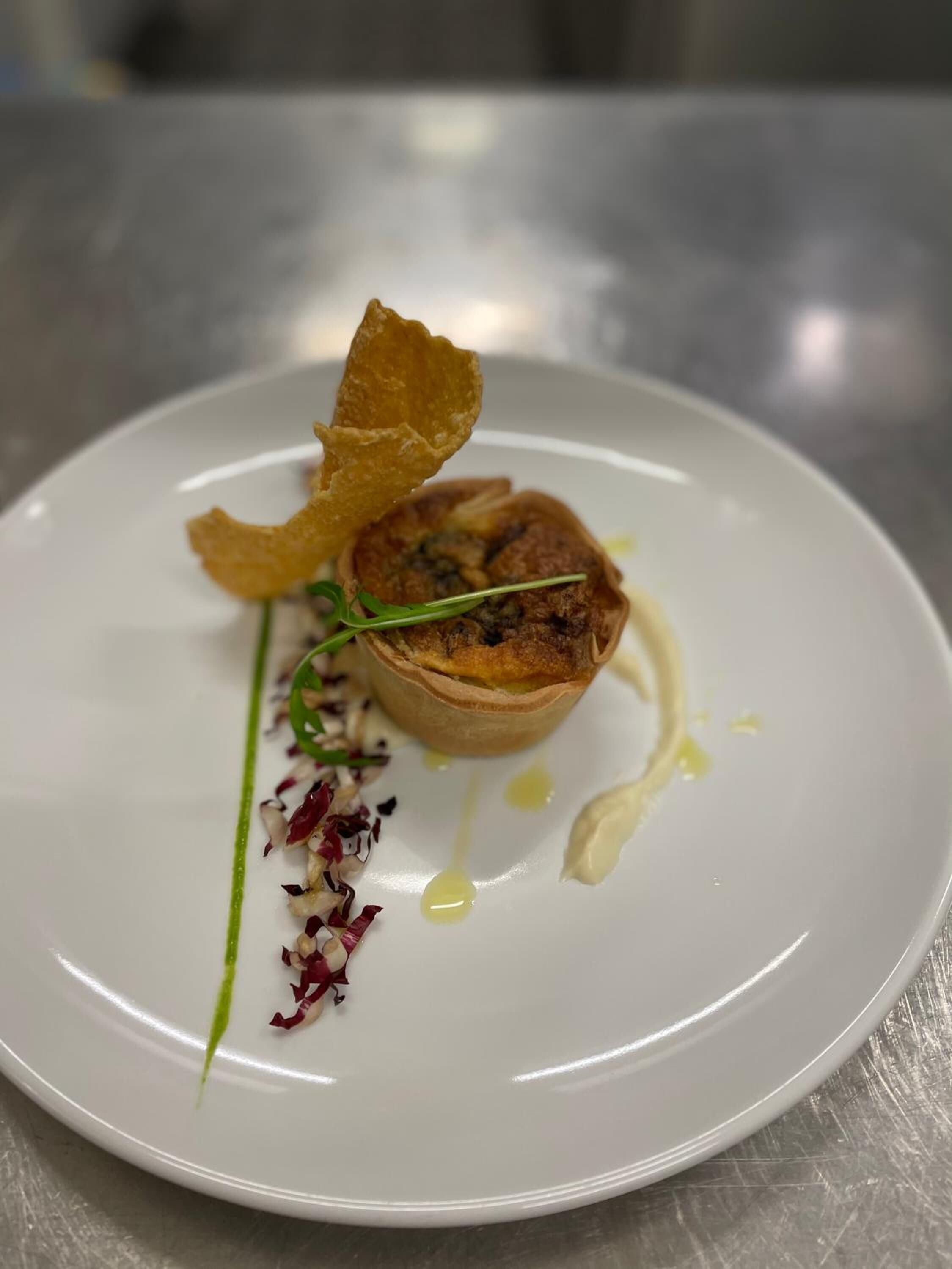 Un plato blanco con una tarta, un bocado crujiente y algunas guarniciones.