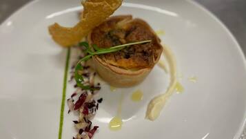 Un plato blanco con una tarta, un bocado crujiente y algunas guarniciones.