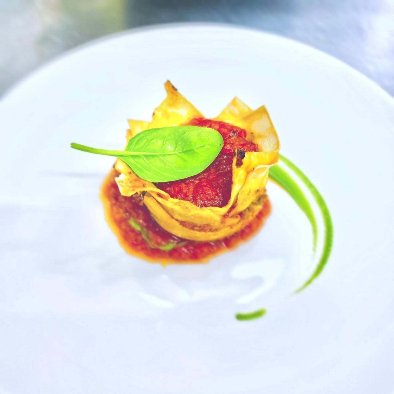 Un plato con salsa roja y una hoja verde como decoración.