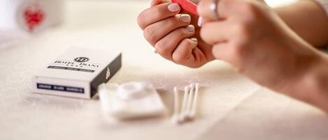 A hand holding a red object, a box labeled "HOTEL HD," and a cotton swab on a table.