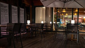 An indoor dining area with wooden flooring, tables, chairs, and a large umbrella. - Hotel Diana (Valdobbiadene)