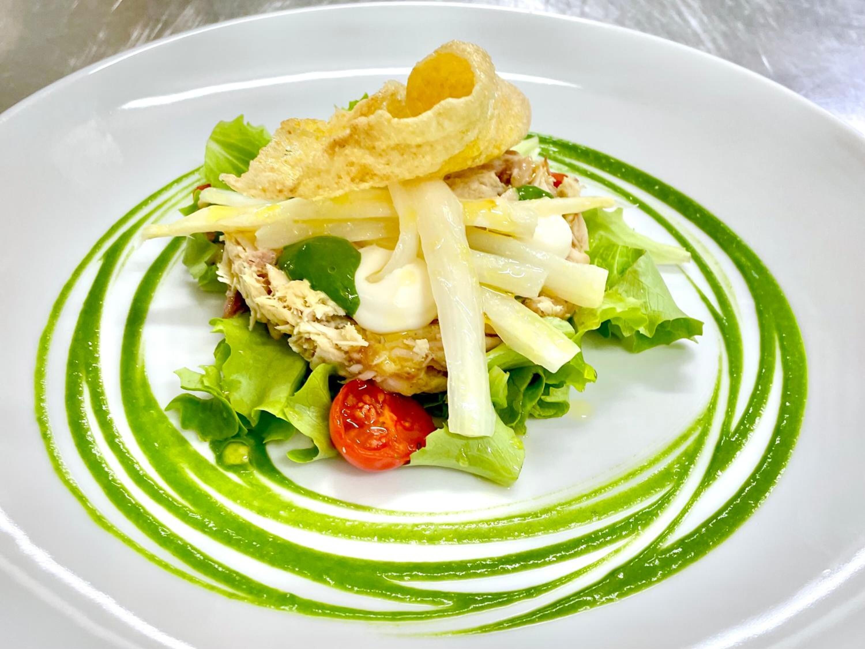 Un piatto di cibo con salsa verde e un elemento croccante sopra.